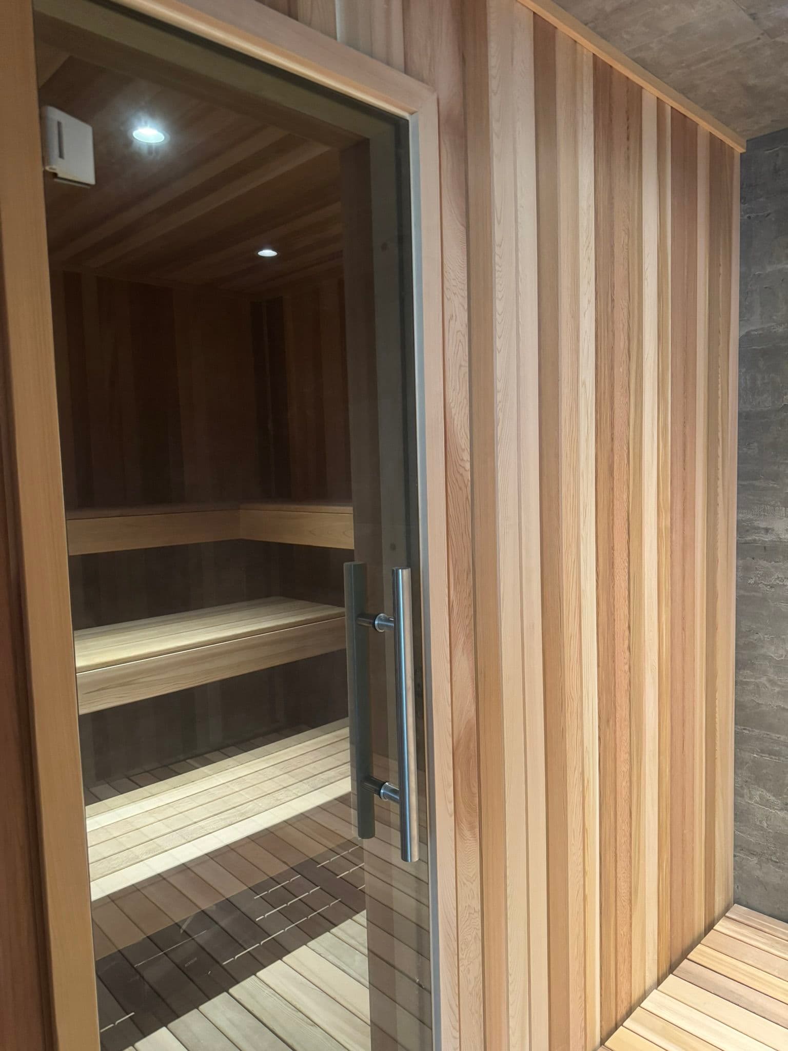 Modern wooden sauna interior featuring cedar panels and bench seating. Relaxation space.
