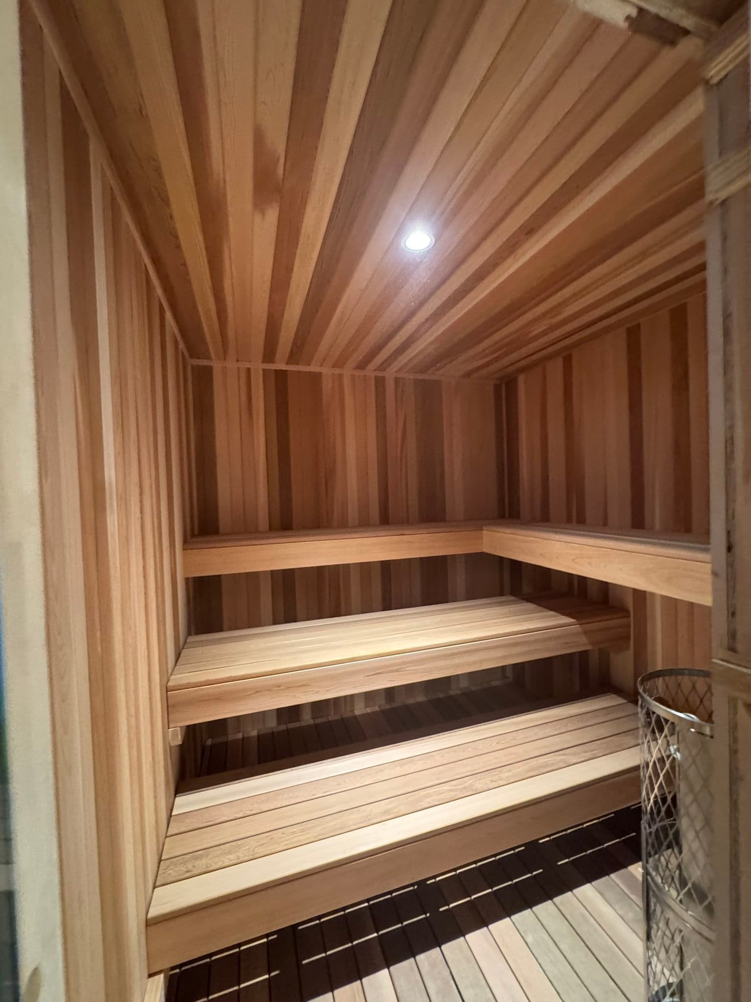 Interior of a wooden sauna with benches and warm lighting. Ideal for relaxation and wellness.
