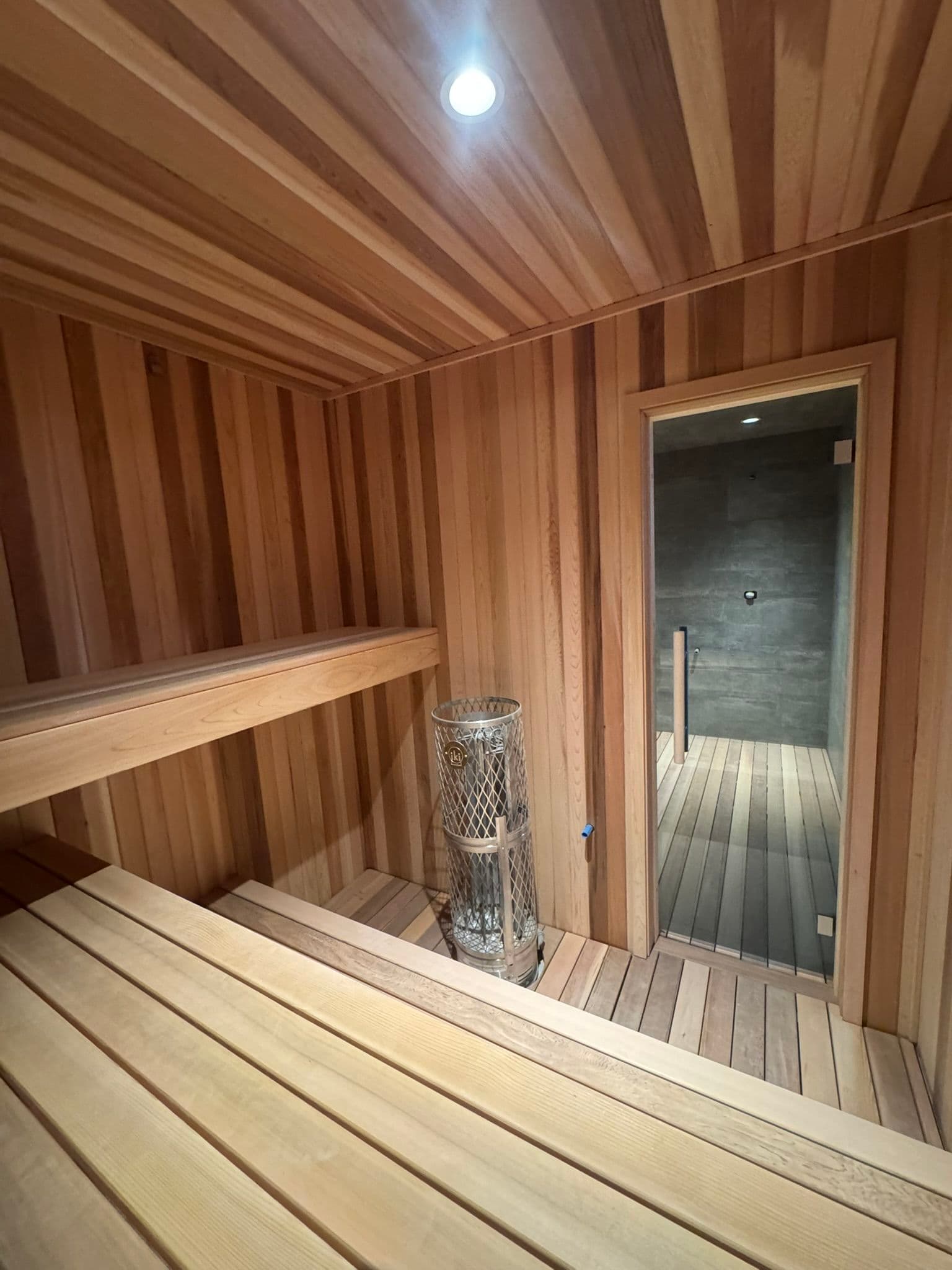 Interior view of a wooden sauna with benches, heater, and dim lighting. Relaxation space.